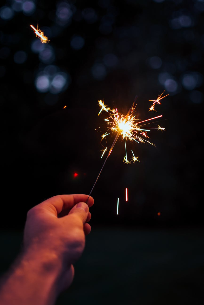 selective focus photography person holding lighted sparkler at nighttime