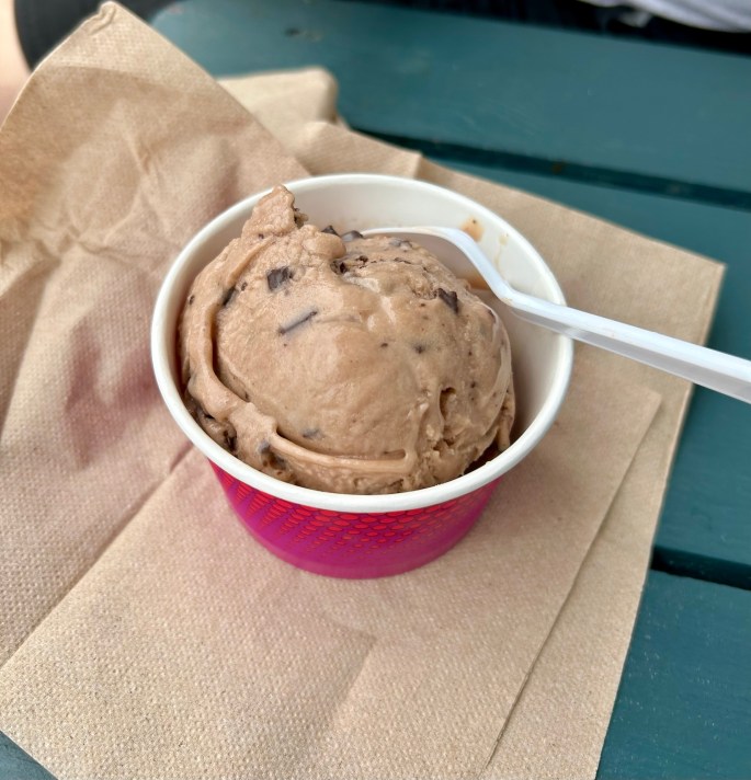 A cup of chocolate ice cream with chocolate chunks on a paper napkin.