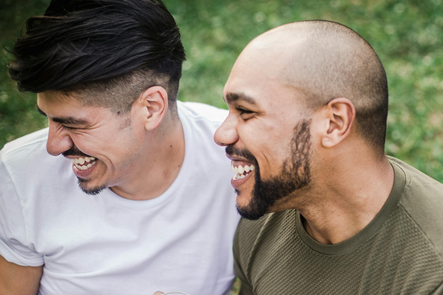 Two men laughing together outdoors, enjoying a moment of joy in a natural setting.